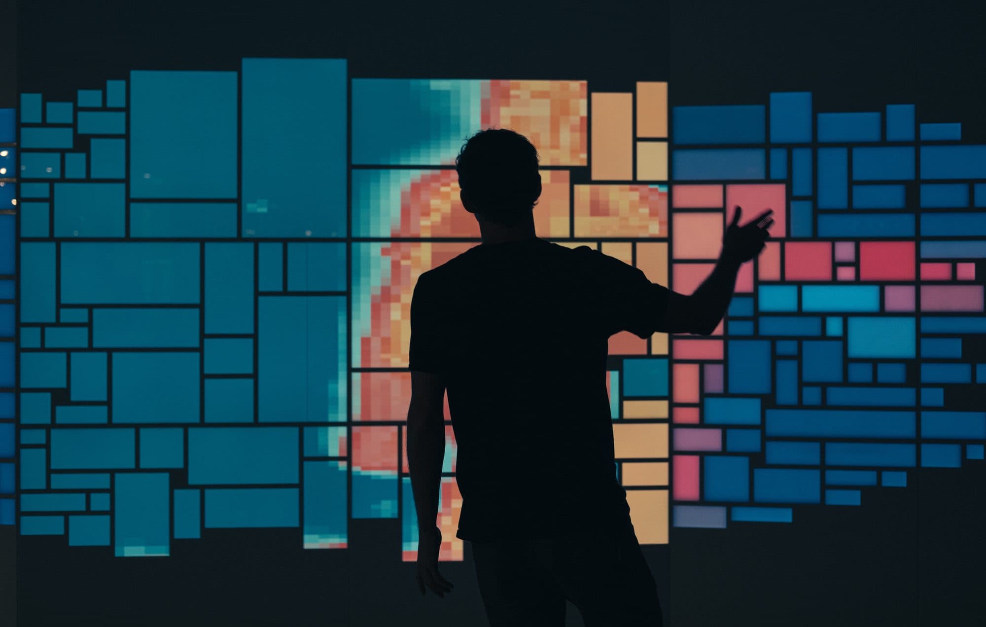 Silhouette of a person interacting with a large-scale data visualization wall